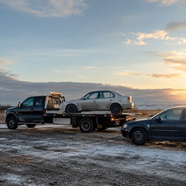 Scrap car loaded onto a flatbed tow truck
